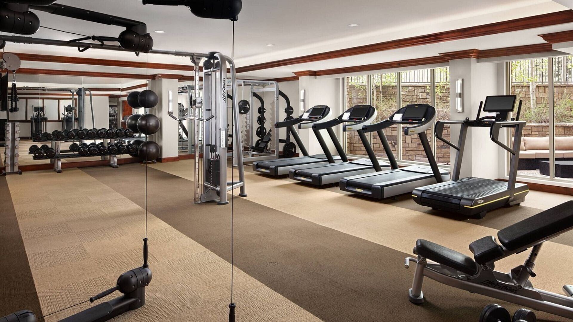 Une salle de sport équipée de tapis de course, d’appareils de musculation et d’haltères.
