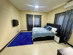 Une chambre à coucher avec un lit, une télévision, un bureau et des rideaux.