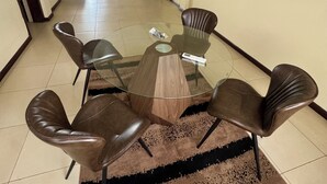Un salón de conferencias con una mesa de vidrio, cuatro sillas de cuero y una alfombra de pelo corto color marrón.