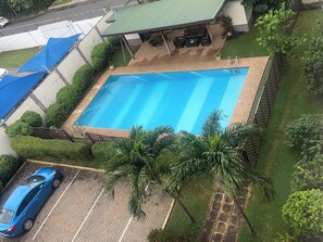Une piscine rectangulaire, bordée d’une terrasse carrelée, entourée d’un espace verdoyant bien entretenu et dotée d’un coin salon abrité.