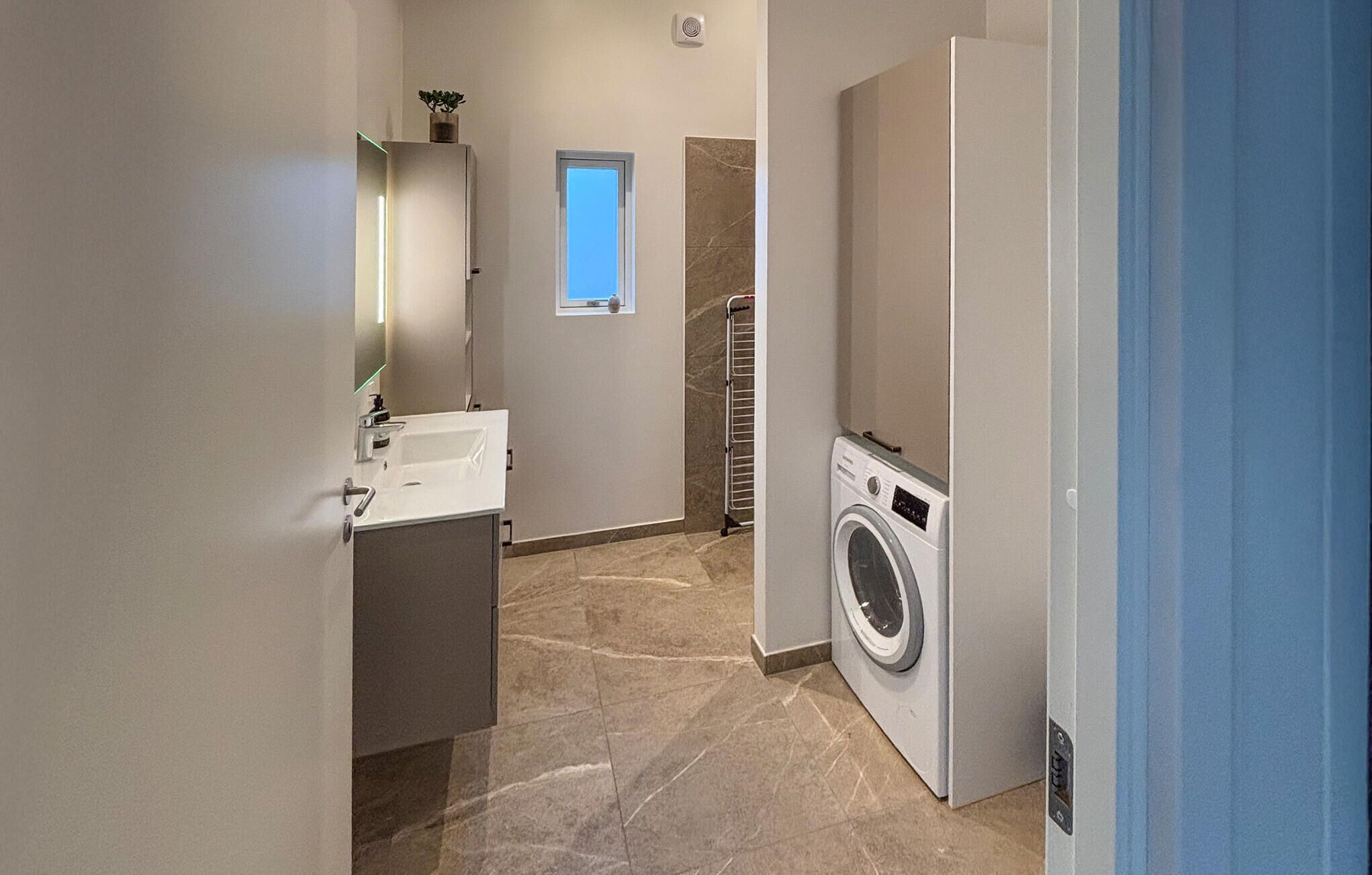Une petite buanderie équipée d’un lave-linge, d’un étendoir et d’une petite fenêtre.