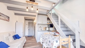Een knus leefruimte met een eethoek, kitchenette en een trap.