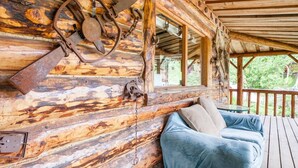 A rustic cabin with a wooden deck, a cozy seating area with a blue sofa, and a rustic metal decoration on the wall. - Cozy Log Retreat Near Turnagain Arm (Anchorage)
