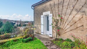 Un edificio con una puerta blanca y un pequeño jardín con plantas y flores.