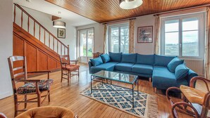 Un salón amplio con una escalera de madera, un sofá modular azul y una mesa de centro de cristal.