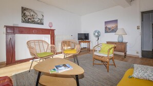 A living room with wicker chairs, a wooden table, a TV, and a fireplace. - 3 bedroom gorgeous apartment in OLMETO (OLMETO)