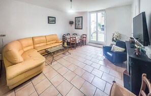 Una sala de estar con sofá, mesa de centro, televisor y comedor con sillas y mesa.
