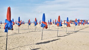 Ein Strand mit Reihen von Strandsonnenschirmen.