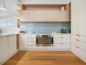 Une cuisine moderne avec des armoires blanches, un four en acier inoxydable et un dosseret de carrelage disposé en motif chevron.