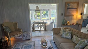 Una sala de estar con sofá, sillón, mesa de centro y vistas a un patio exterior.