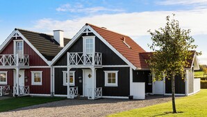 A two-story house with a red and black exterior, white trim, and a gravel driveway. - Amazing home in Brenderup Fyn with sauna (Brenderup Fyn)