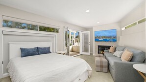 Une chambre moderne avec un grand lit, un canapé gris et une cheminée.