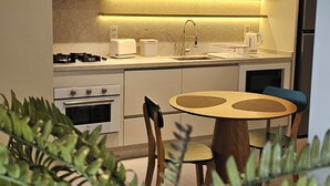 A modern kitchen with a round table and chairs, a built-in oven, and a sink. - eStudio Central 506 (Florianópolis)