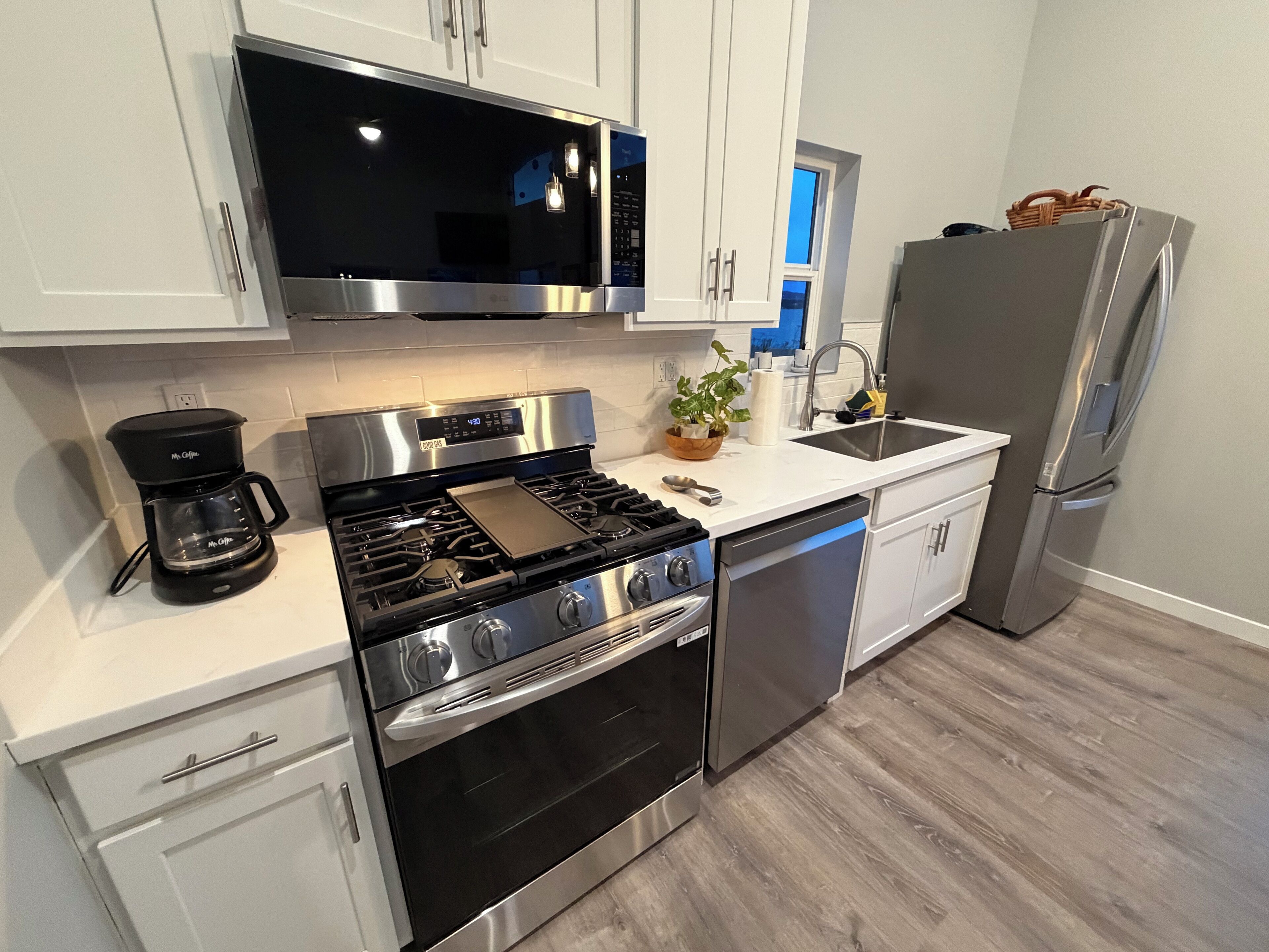 A modern kitchen with stainless steel appliances, a coffee maker, and a sink.