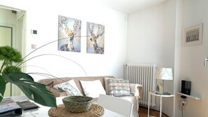 A modern living room with a white sofa, a coffee table with a woven placemat, and two wall-mounted paintings. - Beautiful apartment with terrace. Centrally located between St. Mark's Square and Rialto! (Venedig)