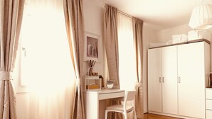 A bedroom with a bed, a desk with a chair, a wardrobe, and a window with curtains. - Beautiful apartment with terrace. Centrally located between St. Mark's Square and Rialto! (Venedig)
