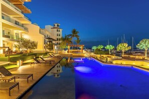 A swimming pool with lounge chairs and a view of the marina at dusk. - Vista Coral 106 - Ground Floor Unit - Marina View (La Paz)