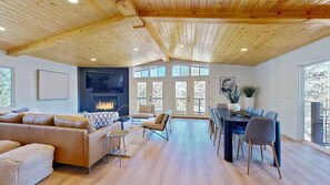 A spacious living room with a fireplace, a dining area with a large table and chairs, and a cozy seating area with a sofa and armchairs. - Tranquil 3-bedroom cabin with AC in charming Alto (Alto)
