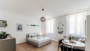 Een moderne, goed verlichte kamer met een bed, een eettafel met stoelen en een bank.