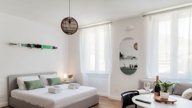 Een moderne slaapkamer met een bed, nachtkastje en een zithoek met een tafel en stoelen.