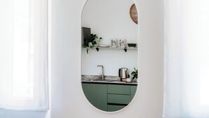 Een moderne keuken met een groen aanrecht, witte kasten en een ronde spiegel die de ruimte weerspiegelt.
