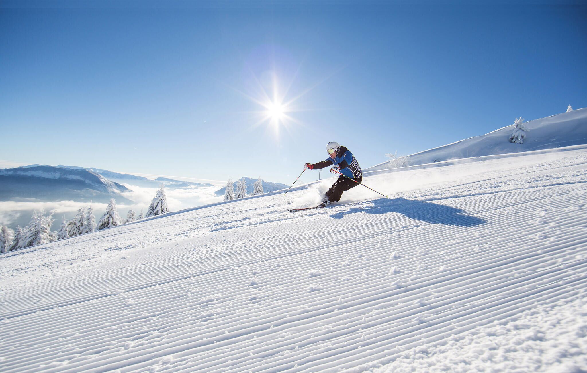 A skier on a snowy slope with a clear sky and distant mountains.