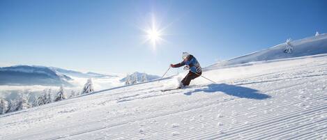 A skier on a snowy slope with a clear sky and distant mountains.