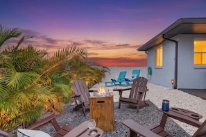 A patio with outdoor seating, a fire pit, and a view of a house at sunset. - Your Private Slice of Paradise | Sleeps 14 | 3 Miles to Beaches! (Bradenton)