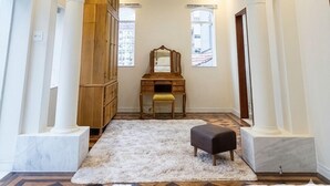 A hallway with a wooden wardrobe, a mirror, a bench, and a rug.