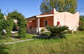 A house with a porch, a stone wall, and a red fire extinguisher.