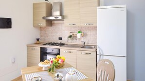 Een moderne keuken met houten kastjes, een roestvrijstalen afzuigkap, een ingebouwde oven, een spoelbak en een witte koelkast.