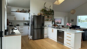 Eine moderne Küche mit weißen Schränken, einem Edelstahlkühlschrank und einer Holz Arbeitsplatte.