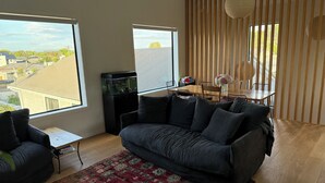 Ein modernes Wohnzimmer mit einem dunkelgrauen Sofa, einem kleinen Couchtisch und einem Aquarium.