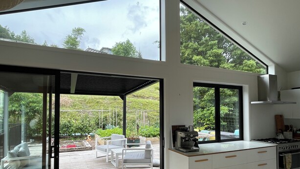 Eine moderne Küche mit großem Fenster, einem Essbereich mit weißer Möbel und Blick auf den Garten.