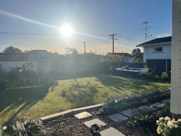 A residential backyard with a lawn, a boat, and a house in the background.