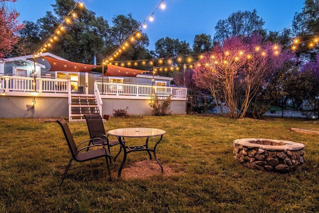 A backyard with a covered patio, outdoor seating, and a stone fire pit.