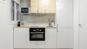A modern kitchen with white cabinets, a built-in microwave, a stainless steel sink, and a black oven. - Chueca Center II - Studio for 4 in downtown Madrid (Madrid)