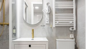 A modern bathroom with a gold faucet, a white sink, a toilet, and a towel rack. - Chueca Center II - Studio for 4 in downtown Madrid (Madrid)