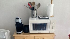 A kitchen area with a microwave, a coffee maker, and a cabinet with wooden doors. - Studio for 4 to 5 people, "Edelweiss" with mountain view balcony (Le Biot)