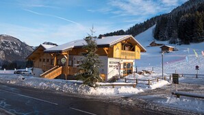 A wooden mountain lodge with a restaurant sign, surrounded by snow-covered mountains and a clear sky. - Studio for 4 to 5 people, "Edelweiss" with mountain view balcony (Le Biot)