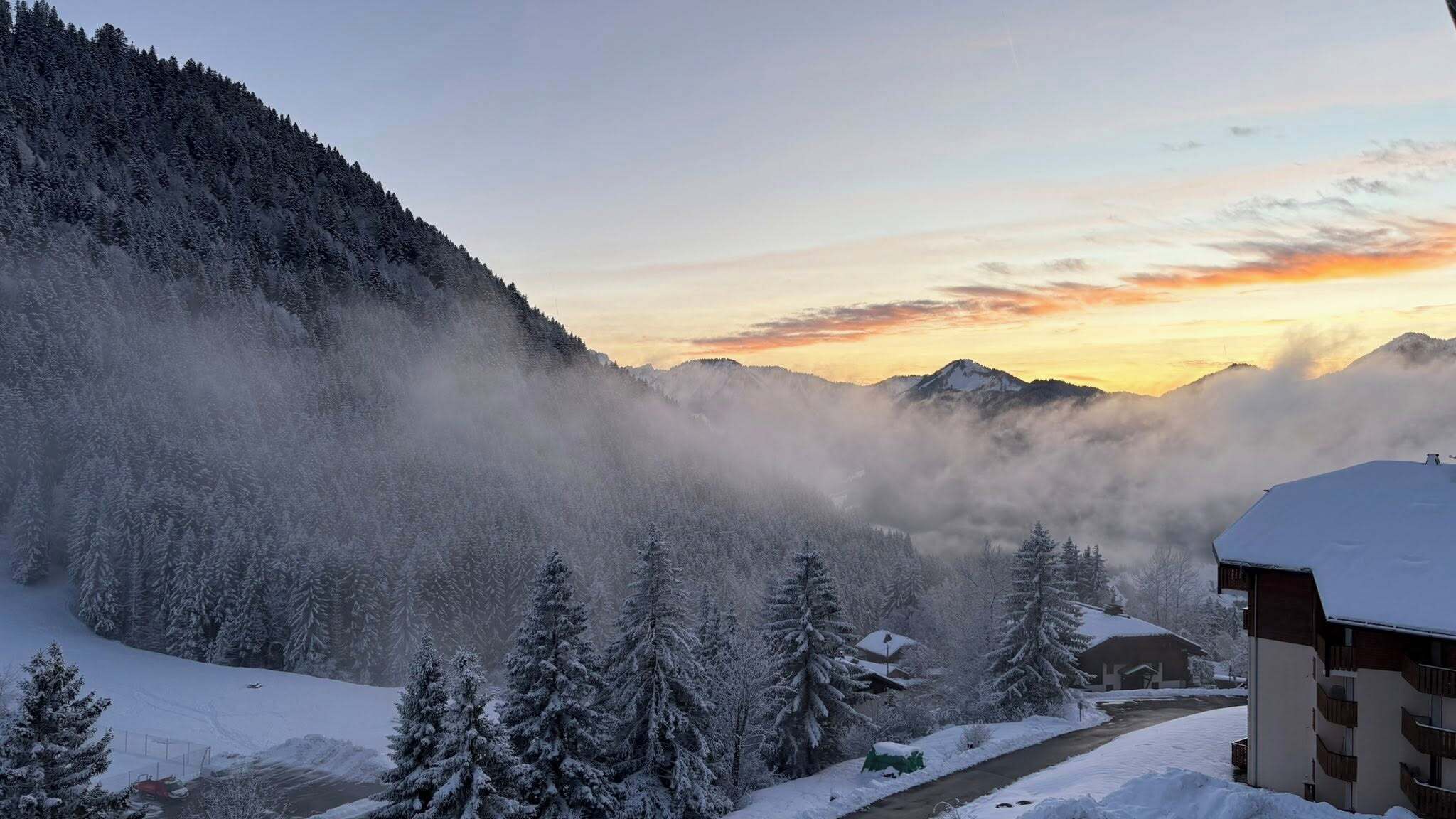 A snow-covered mountain landscape with a building in the foreground.