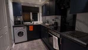 Una cocina compacta con lavadora, microondas y electrodomésticos modernos.