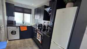 Una cocina compacta equipada con lavadora, refrigerador y lavamanos.