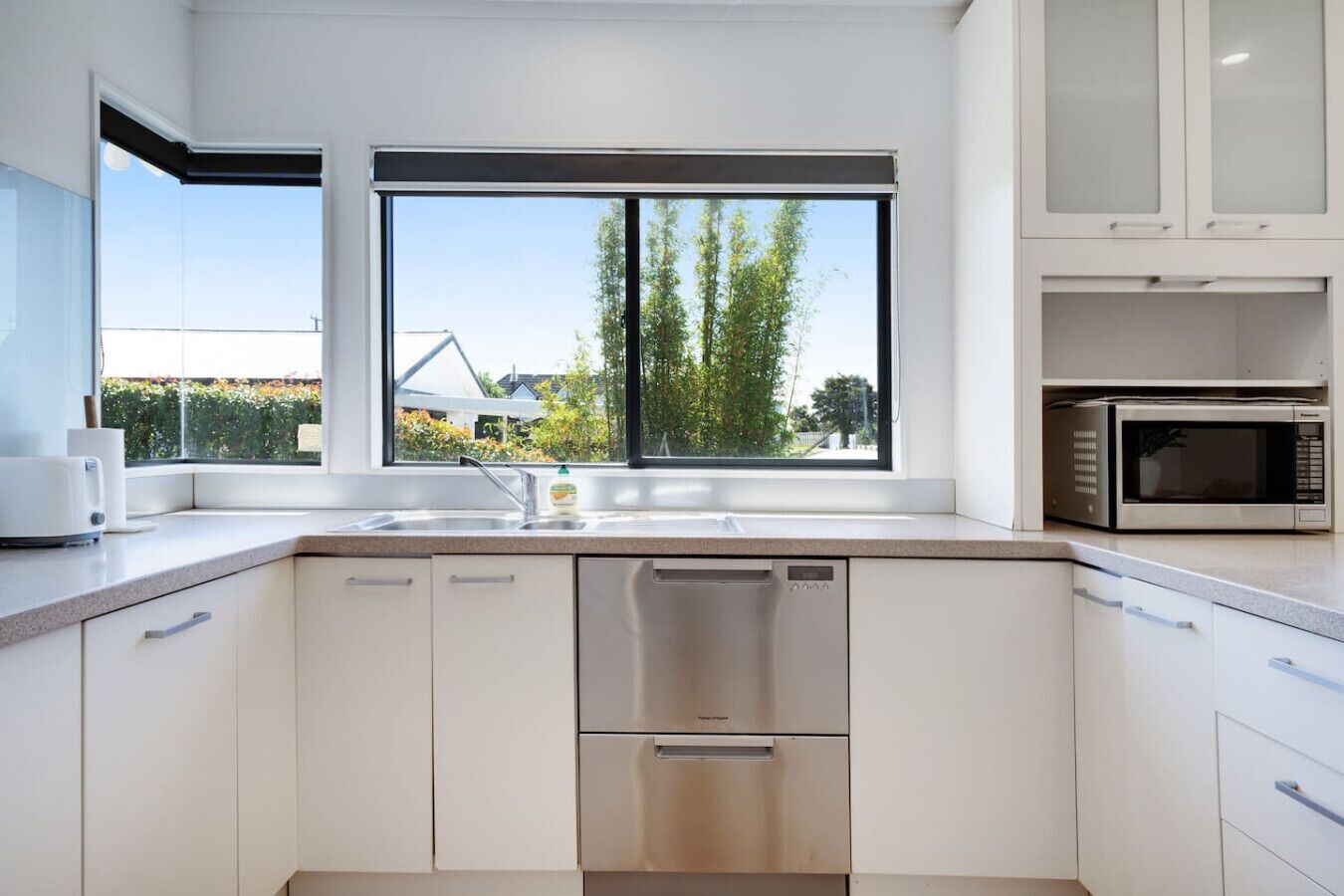 A modern kitchen with a built-in dishwasher, a microwave, and a large window offering a view of the outside.