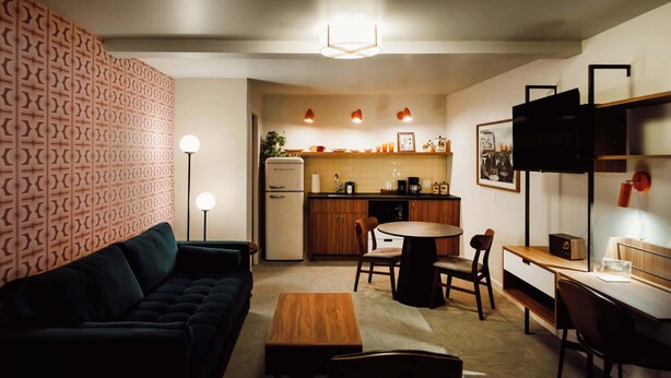 Un espace de vie compact comprenant un canapé, une table à manger et un coin cuisine.