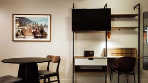 Une pièce de taille modeste, équipée d’un bureau, d’une chaise et d’un téléviseur fixé au mur.