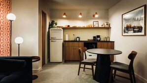 Une cuisine compacte équipée d’un réfrigérateur, d’une machine à café et d’une table à manger avec des chaises.
