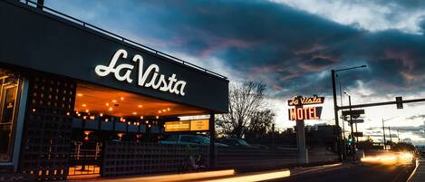 A motel named La Vista with a neon sign, a visible entrance, and a street view with cars passing by.