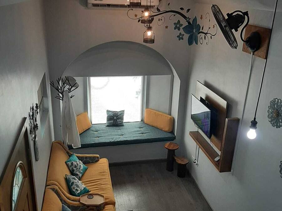 A compact living space with a built-in bench, a sofa, a TV, and a small table.