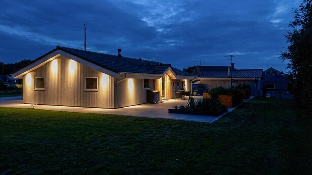 Une maison moderne avec une allée bien éclairée et un petit jardin.